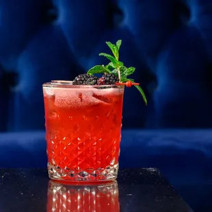 a red cocktail with a sprig of mint