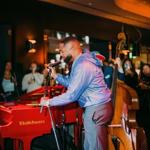 a man playing the piano and singing into a microphone
