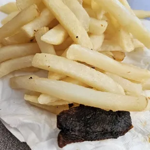 Undercooked cooked fries and burnt bacon.