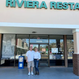 two people standing in front of the restaurant