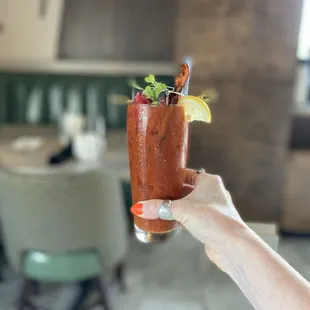 a person holding a bloody drink in a restaurant