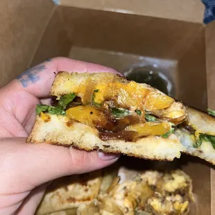  hand holding a half eaten pizza