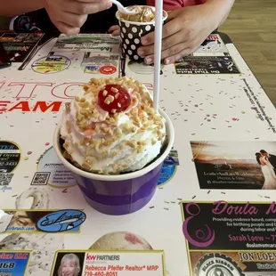 a woman sitting at a table with an ice cream sundae