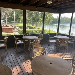 tables and chairs on a deck overlooking a lake