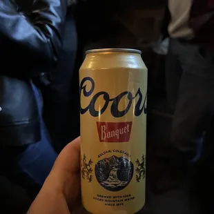 a person holding a can of beer