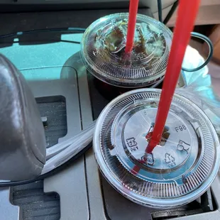 a close up of two cups of coffee on the dashboard of a car