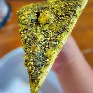 a hand holding a piece of pizza