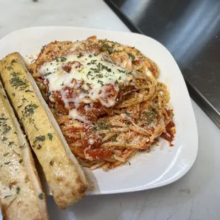 a plate of spaghetti and breadsticks