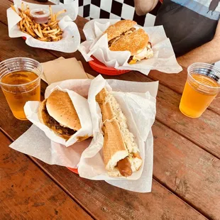 a man sitting at a table with three sandwiches and fries