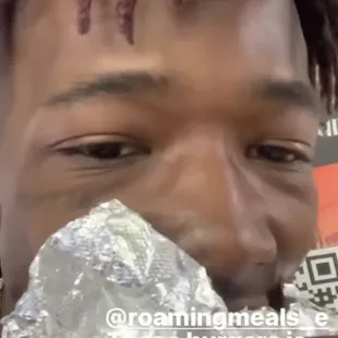 This customer eating a #5 Pepperoni Pizza Gusherburger  pepperonis and cheese inside the pizza leaking out topped with pizza sauce