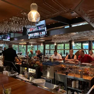 people sitting at a bar watching televisions
