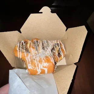 a hand holding a donut in a box