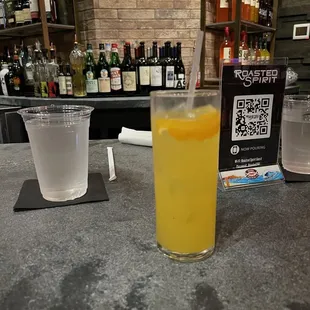 a glass of orange juice on a bar counter