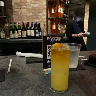 a glass of orange juice on a bar counter