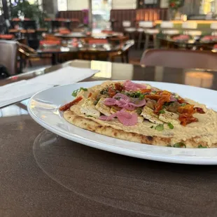 Indian curry spiced tofu flatbread topped with onions, capers, and sundried tomatoes, and a hummus sauce