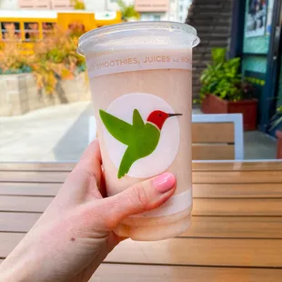 a hand holding a cup of smoothie