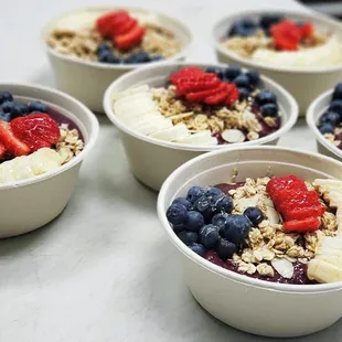 four bowls of fruit and yogurt