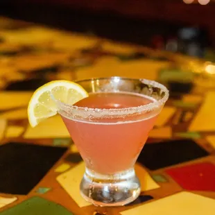 a pink cocktail with a slice of lemon