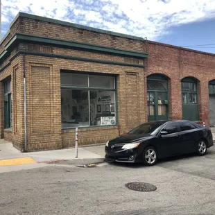 a black car parked in front of a brick building