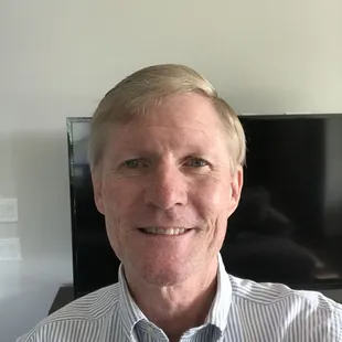 a man smiling in front of a television