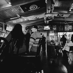 a black and white photo of people sitting at a bar