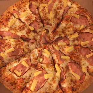 a pizza with ham and pineapple toppings