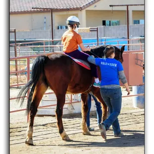 Volunteer Sidewalker assisting a therapeutic rider during class