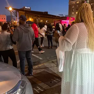 a woman in a white dress standing on a city street
