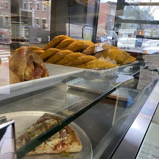 a plate of pizza and pastries in a display case