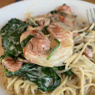 a plate of pasta with shrimp and spinach