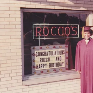 a woman in a graduation gown standing in front of a window