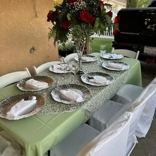 Tables, chairs, chair covers, tablecloths, table overlays, floral arrangement, plates, silverware, center piece