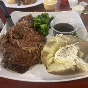 Prime rib with baked potato and broccoli.