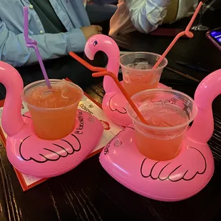 two pink flamingo drink holders on a table