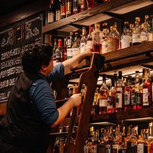 Bartender pulling down a bottle of scotch