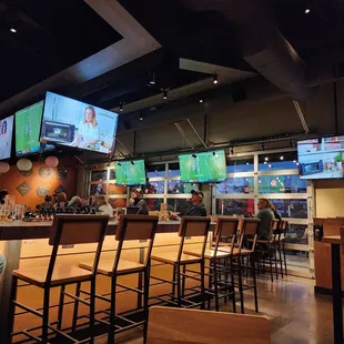 a man sitting at a bar watching televisions