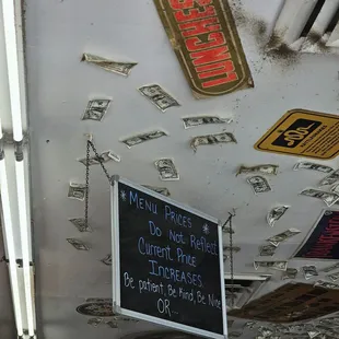 Sign addressing the lack of menu pricing; zoom in to see the extent of the dust and grime