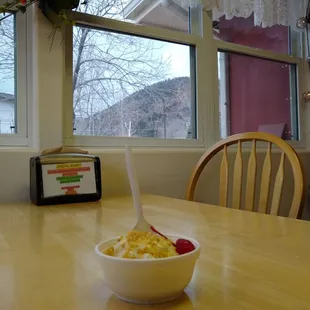 Butterscotch sundae, chair, and window. There's a storm rolling in over the mountains.