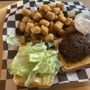 a burger with lettuce and tater tots