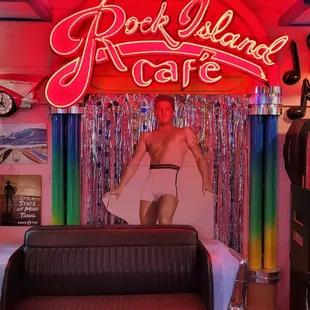 a man standing in a chair in front of a neon sign