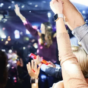 ows a crowd of people with their hands in the air