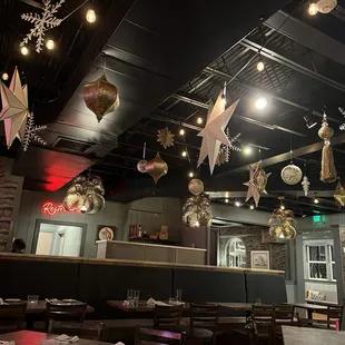 tables and booths with christmas decorations hanging from the ceiling