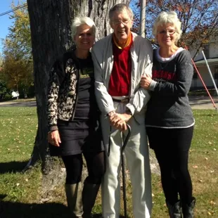 a man and two women standing next to a tree
