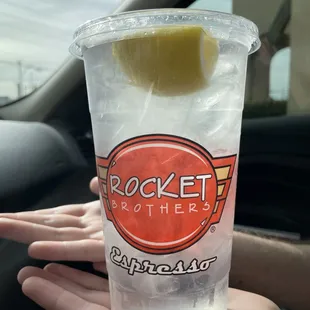 a hand holding a cup of ice and a lemon