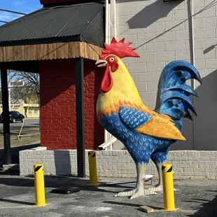 a colorful rooster statue in front of a restaurant