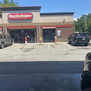 the outside of a restaurant with cars parked in front of it