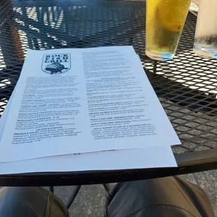 Menu and glass of pineapple cider at an outside table