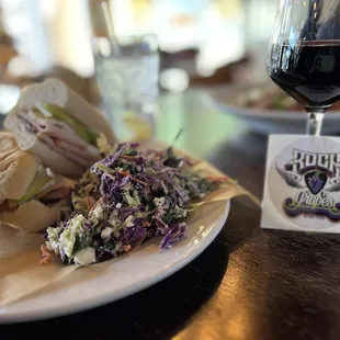 Turkey Bam Brie Lam and Fig Jam sandwich with a side of kale slaw and a glass of Chronic Cellars Purple Paradise.