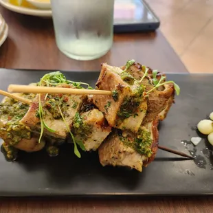 meat skewers on a black plate