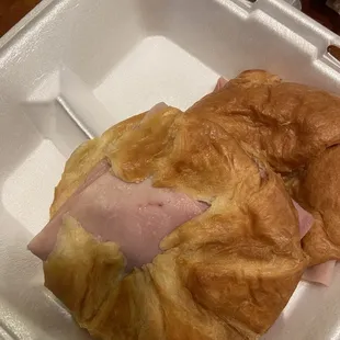 a croissant sandwich in a styrofoam container